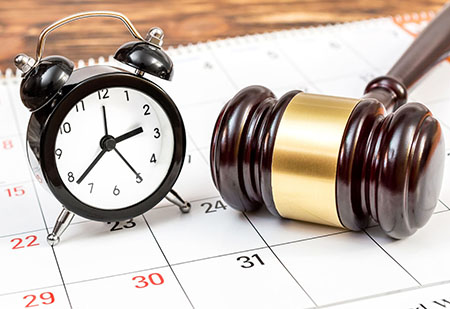 Photo of gavel and clock sitting on a calendar.