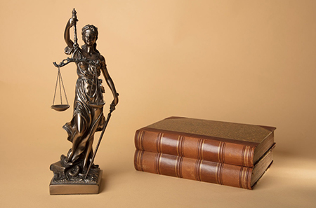 Photo of scales or justice and a law book.