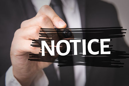 Photo of hand holding the word notice.