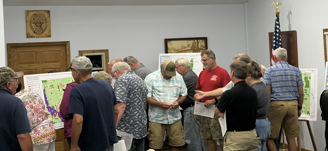 Group of people looking at maps at first land use meeting.